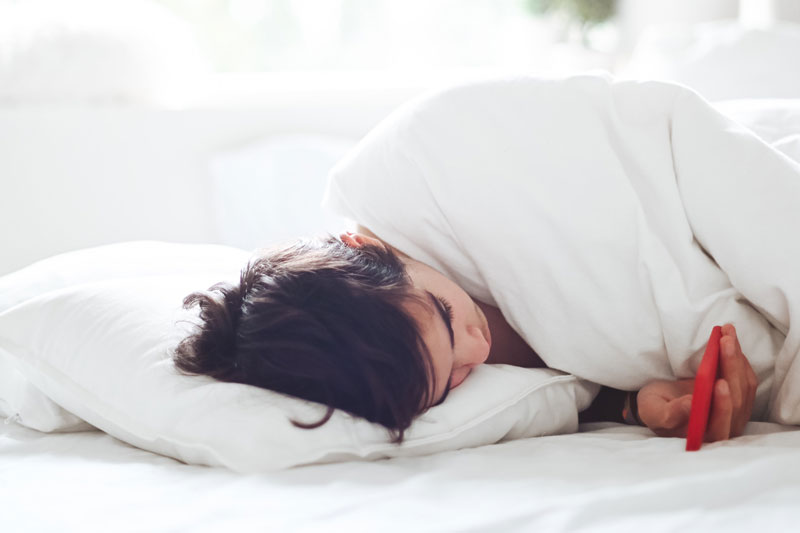 Kind mit Smartphone im Bett