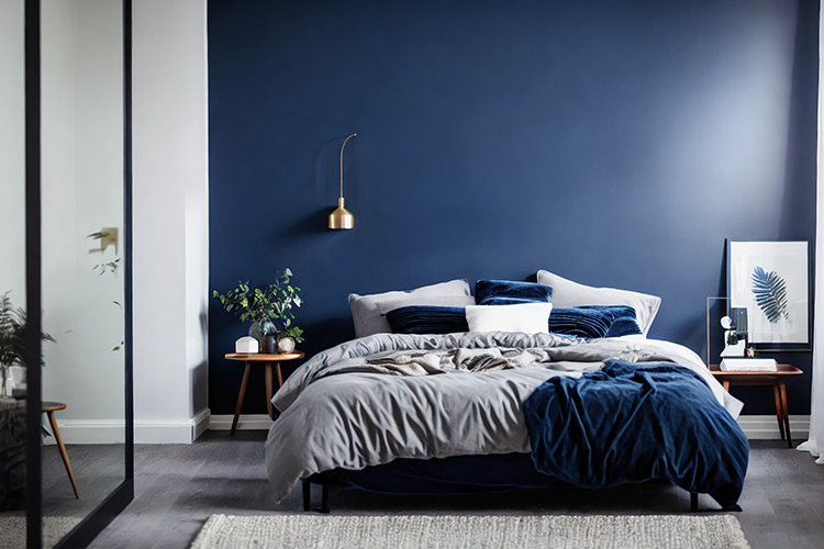 Bild zeigt dunkles Bett mit blauer Wandfarbe