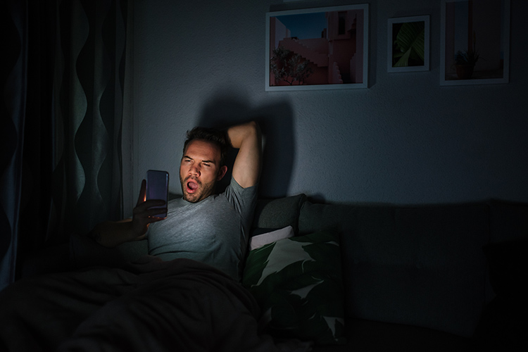Bild zeigt Frau mit Handy im Bett